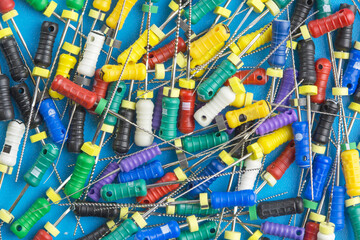 Endodontic tools, k-files, h-files, reamers, barbed broaches close up on a blue background.