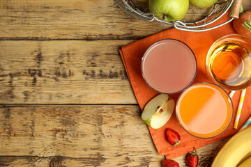 Glasses of delicious juices and fresh fruits on wooden table, flat lay. Space for text