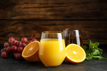 Glasses of delicious juices and fresh fruits on black table
