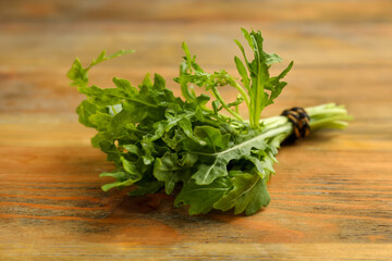 Bunch of fresh arugula on wooden table, closeup
