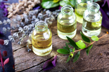 Lavender essential oil in a little bottles on wooden background. Aromatherapy tools, bottles with oil and lavender flowers.