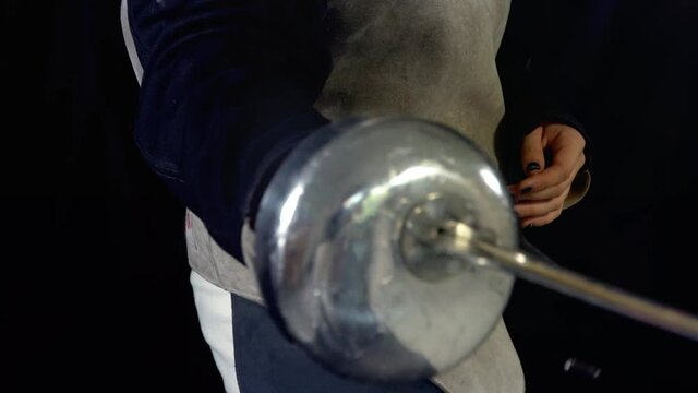 Fencing teacher holding weapon for private lessons. Class in epee fencing skills for women.