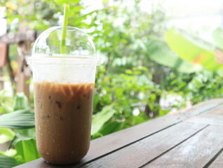 Iced coffee in plastic mug on wood and natural background.