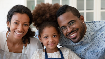 Head shot close up portrait of smiling african ethnicity parents posing for photo with adorable...