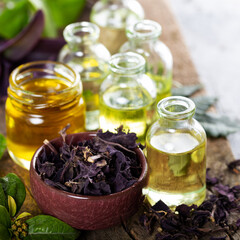 A bottle of basil essential oil with dried basil leaves and flowers,