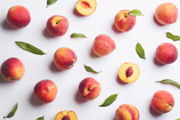 Fresh ripe peaches and green leaves on white background, flat lay
