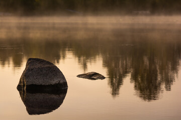 A boulder in a lake with fog