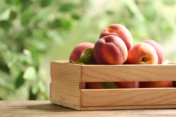 Fresh sweet peaches in wooden crate on table outdoors