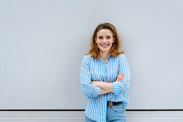 Happy friendly woman standing with folded arms