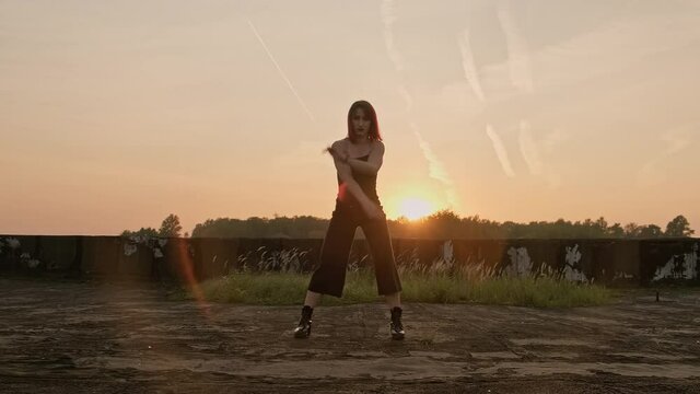 Young talented female dancer performing freestyle moves enjoying modern dance. Dancing girl on roof at sunset. Freestyle dance improvisation. Full length in 4K, UHD
