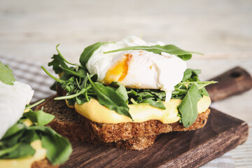 Delicious sandwich with arugula and egg on wooden board, closeup