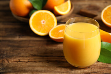 Glass of orange juice and fresh fruits on wooden table