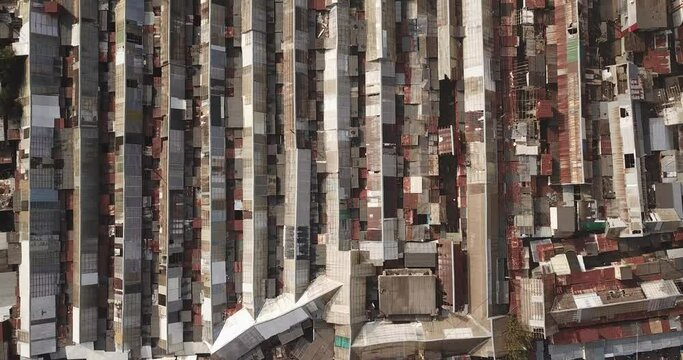 Aerial top-down view high altitude of slum a heavily populated urban informal settlement characterized by substandard housing and squalor poor living conditions streets and rusty metal home roof tops