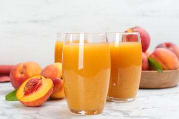 Natural peach juice and fresh fruits on white marble table, closeup