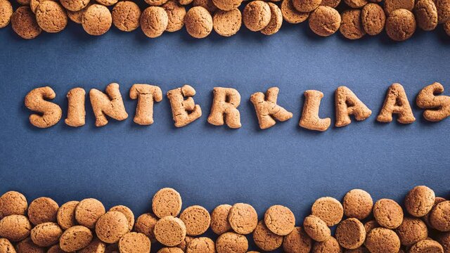 Stop motion animation. Sinterklaas is coming soon, 4K. Dutch holiday St Nicholas day concept with letters traditional cookies, kruidnoten on blue background with copy space. Top view.
