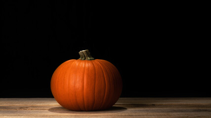 Pumpkin on old dark rustic wooden table. Halloween background with pumpkin. Autumn, Halloween concept. Copy space.