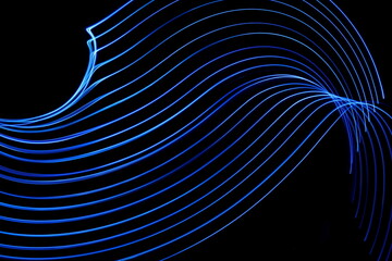 Long exposure photograph of neon blue colour in an abstract swirl, parallel lines pattern against a black background. Light painting photography.