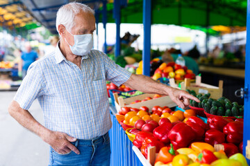 retired european man wearing medical mask protecting against virus buying tomatoes in market