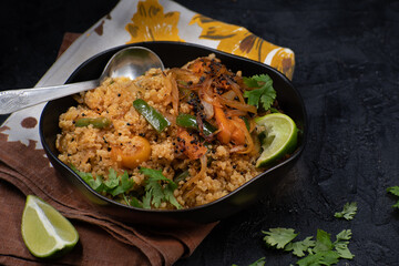 Quinoa pilaf with roasted peppers, sliced onion and spices ib=n black bowl, copyspace