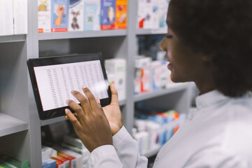 Close-up cropped shot of African American woman doctor or clinical pharmacist using digital tablet...