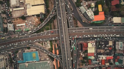 Slow motion top down of cross road traffic with cars, trucks, vehicles in aerial view. Downtown of Manila city with colorful buildings roofs at roadside. Philippines urban lifestyle with local journey