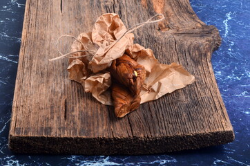 Dried melons in a paper bag, close-up, on a wooden background.