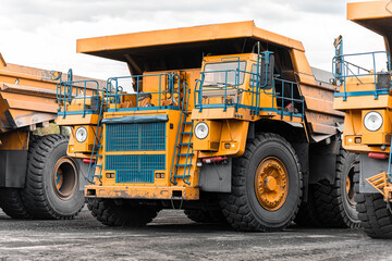 Fototapeta na wymiar Large quarry dump truck. Big yellow mining truck at work site. Loading coal into body truck. Production useful minerals. Mining truck mining machinery to transport coal from open-pit production