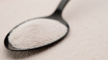 collagen powder in spoon on collagen powder background. Natural beauty and health supplement