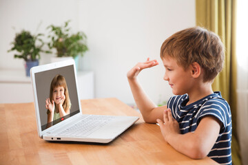 kid boy making online video call  with child girlfriend on digital laptop at home, looking at computer screen. Distancing. copy space.