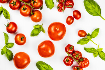 different tomatoes and basil on white background