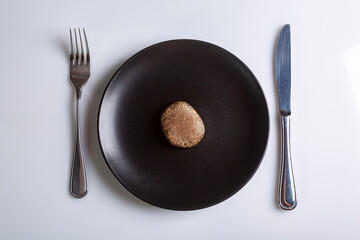 Raw one Jersey cow mushroom in a black plate and a knife and fork nearby on a white background top view. Horizontal orientation. High quality photo