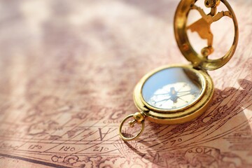 Retro styled golden antique compass (sundial) and old white nautical chart close-up. Vintage still...