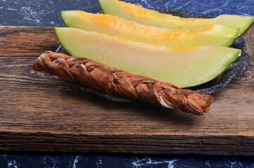 Dried melon and fresh melon slices on a wooden background.