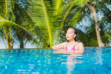 Fototapeta premium Portrait beautiful young asian woman smile relax around outdoor swimming pool in resort