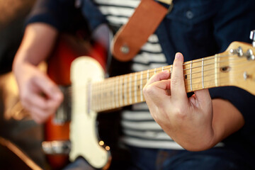 close up hand young man playing electric guitar at recording studio rehearsal base. rock music band.