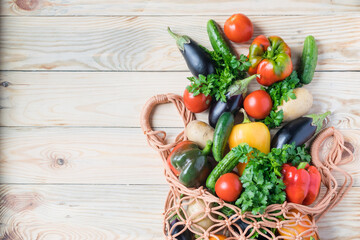Net shopping eco friendly bag with organic vegetables on wooden background. Zero waste, plastic free concept. Top view, flat lay, copyspace
