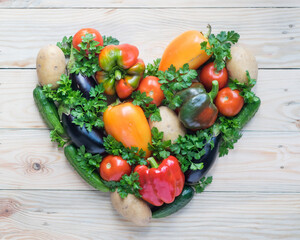 Fresh organic vegetables in shape of heart on light wooden background. Vegan and healthy eating concept
