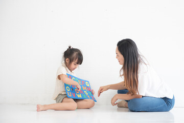 Young Asian mother taught her little daughter about reading English characters, family concept