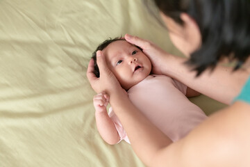 Obraz na płótnie Canvas Mother’s hands holding head of cute Asian little baby girl