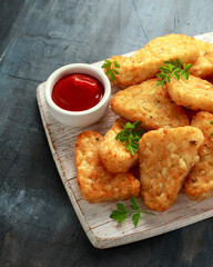 Hash brown potato with ketchup on white wooden board