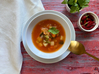 Vegetarian, healthy vegetable minestrone soup is made with red and yellow carrots, onions, garlic, celery, potatoes, diced tomatoes, tomato paste, parsley, green peas and oregano. Copy space for text.