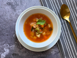 Vegetarian, healthy vegetable minestrone soup is made with red and yellow carrots, onions, garlic, celery, potatoes, diced tomatoes, tomato paste, parsley, green peas and oregano. Copy space for text.