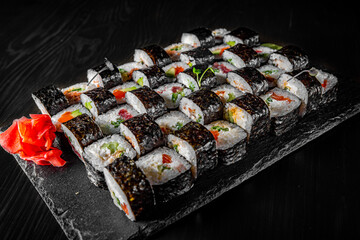set of sushi roll with salmon, avocado, cream cheese, cucumber, rice, caviar, eel in plate on black wooden table background