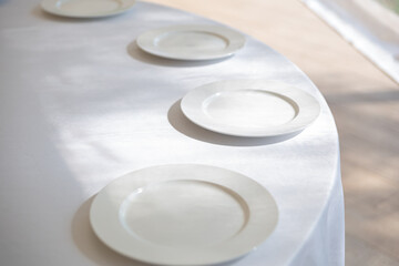 Table setting element empty plates with cutlery on white tablecloth.