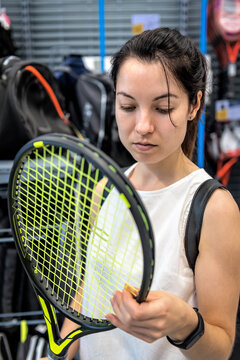 Woman Chooses A Tennis Racket In The Store