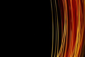 Long exposure photograph of neon red and gold colour in an abstract swirl, parallel lines pattern against a black background. Light painting photography.