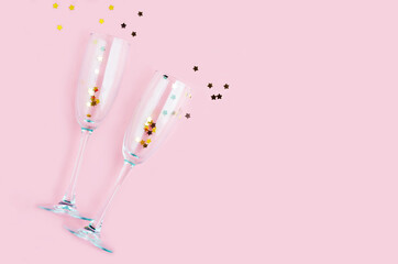 Champagne glass with golden stars confetti on pink color background minimal style, copy space, place for text. party concept