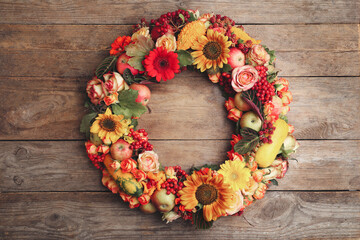 Beautiful autumnal wreath with flowers, berries and fruits on wooden background, top view. Space for text