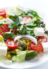 Healthy Salad with Feta Cheese, Green Olives, Baby Spinach, Cucumber, Cherry Tomatoes and Capers. Bright background. Close up.