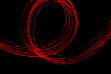 Long exposure photograph of neon colour in an abstract swirl, parallel lines pattern against a black background. Light painting photography.
